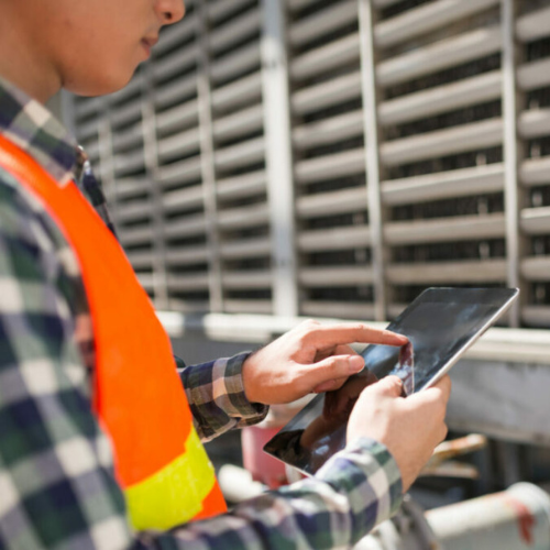 RMBSolutions Mobile App Industrial field technician using a mobile app on a tablet for equipment inspection.