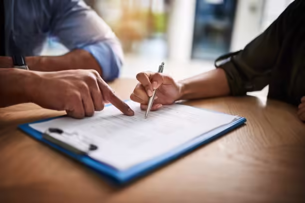 Cropped shot of a man and woman completing paperwork together at a desk Cropped shot of a man and woman completing paperwork together at a desk